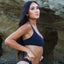 A woman wearing a black bikini top with adjustable straps and a matching bottom,