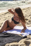 Woman in a black bikini lying on a towel at the beach