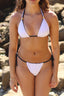 Woman wearing a white bikini with black straps 